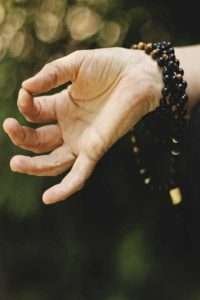 Hand meditating with bead bracelets.  5 Natural Pain Relief Techniques After Knee Replacement. 1. Deep breathing and meditation. Click here to read the rest. 
