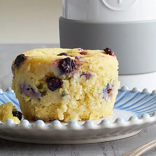 BLUEBERRY LEMON MICROWAVE MUFFIN on a white and blue plate on a table top with a pampered chef ceramic egg cooker in the backgound