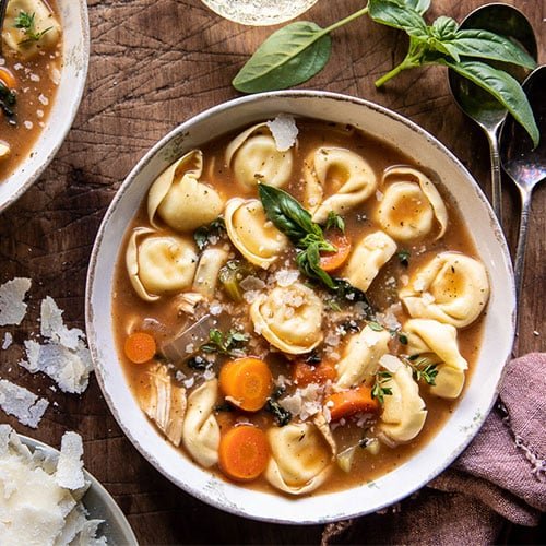 SLOW COOKER TUSCAN TORTELLINI VEGETABLE SOUP on a table inside of a while bowl