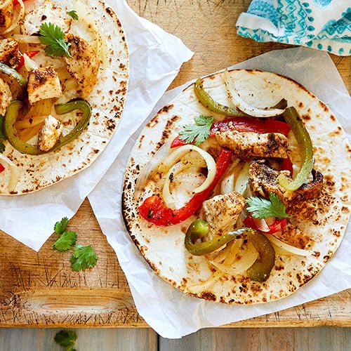 RUSH HOUR CHICKEN FAJITAS on a tortilla shell sitting on a table 